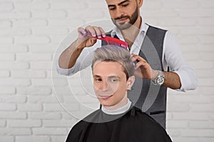 Hairdresser doing hair violet colored toning for young boy.