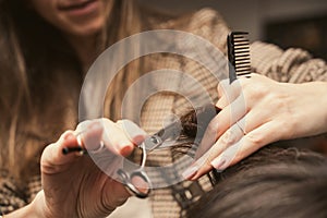 Hairdresser doing haircut closeup of work. Hairstylist does cutting hair tips of a female customer in a beauty salon
