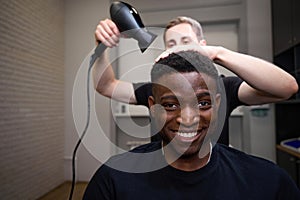 Hairdresser dries African American males hair