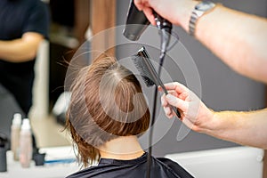 Hairdresser dries brown hair of woman