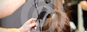 Hairdresser dries brown hair of woman