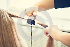 The hairdresser dries and combs a long fair hair. Hairdressing salon.