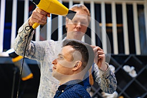 hairdresser dries hair dryer brunette man in a barbershop