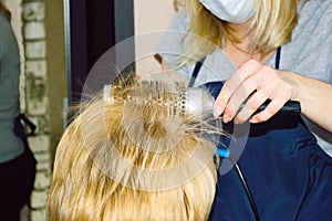 hairdresser dries hair with a hairdryer and styles