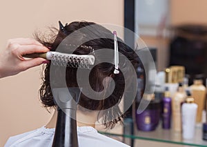 The hairdresser dries her hair a brunette girl