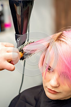 Hairdresser dries pink hair of woman