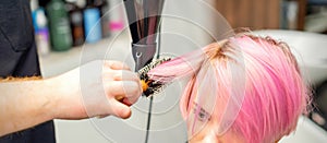 Hairdresser dries pink hair of woman