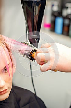 Hairdresser dries pink hair of woman