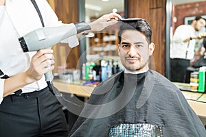 Hairdresser Drying Customer`s Hair With Hairdryer In Salon