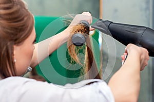 Hairdresser drying long brown hair