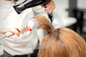 Hairdresser drying long red hair