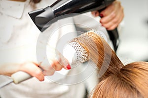 Hairdresser drying long red hair