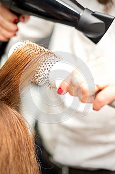 Hairdresser drying long red hair