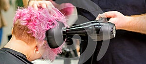 Hairdresser drying short pink hair