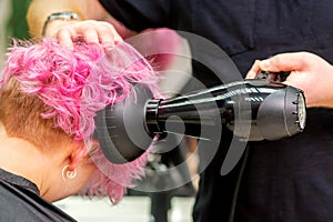 Hairdresser drying short pink hair