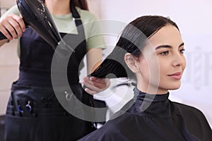 Hairdresser drying woman's hair in beauty salon, closeup