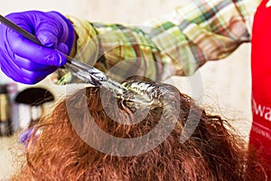 The hairdresser dyes his client`s hair in beauty salon