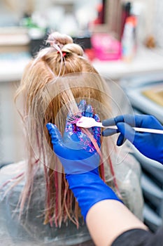 Hairdresser is dying female hair. Hands in glives with brush, coloring in hair salon.