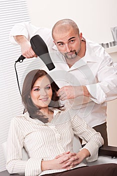 Hairdresser with hair dryer at salon with customer