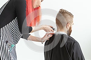 Hairdresser, hairstylist and barber shop concept - woman hairstylist cutting a bearded man