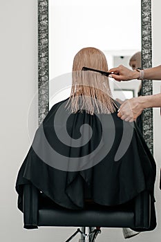 Hairdresser hand with scissors making haircut and hair dye on client closeup photo