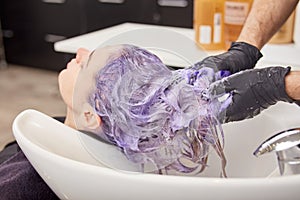 Hairdresser hands applying toning shampoo on woman hair