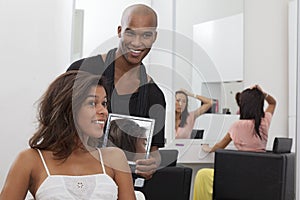 Hairdresser holding a mirror behind young woman photo