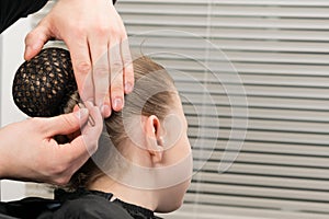 Hairdresser inserts a hairpin under the hairnet