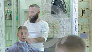 The hairdresser made a stylish haircut for a little boy in barber shop