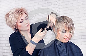 Hairdresser makes a hair cut with scissors