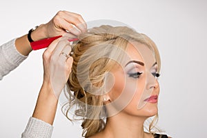 Hairdresser makes hair styling blond girl