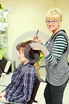 Hairdresser makes hair styling for woman