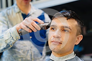 hairdresser makes a haircut of nape for a man with a hair clipper in barbershop