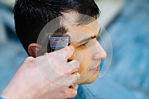 hairdresser makes a haircut of nape for a man with a hair clipper in barbershop