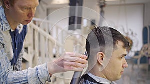 hairdresser makes a haircut of nape for a man with a hair clipper in barbershop