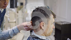 hairdresser makes a haircut of nape for a man with a hair clipper in barbershop