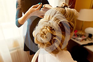 Hairdresser makes hairstyle for the bride. Bride morning.