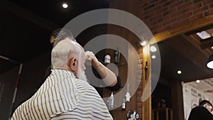 Hairdresser makes new hairstyle for senior man