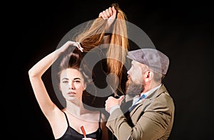 Hairdresser making hair style, haircut. Woman with long hair at beauty salon. Barber cutting hair with scissors.