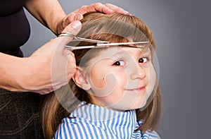 Hairdresser making a hair style to cute little girl