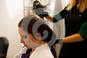 Hairdresser making hair treatment to a customer in salon