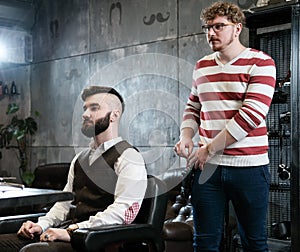 Hairdresser man shaves a client with a beard in a barbershop