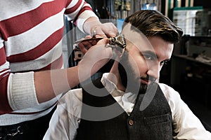 Hairdresser man shaves a client with a beard in a barbershop