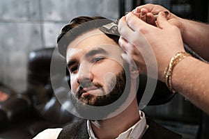 Hairdresser man shaves a client with a beard in a barbershop