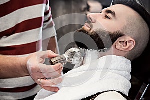 Hairdresser man shaves a client with a beard in a barbershop