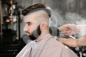 Hairdresser man shaves a client with a beard in a barbershop