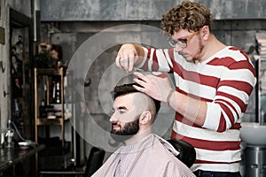 Hairdresser man shaves a client with a beard in a barbershop