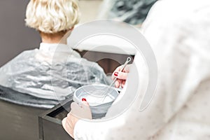 Hairdresser mixing hair dye in a bowl.