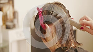 Hairdresser parting, combing, straightening woman`s hair