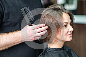 Hairdresser`s hand checking hair of woman